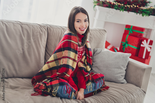 Full size photo of young cheerful girl close herself checkered blanket sit sofa enjoy christmas time indoors