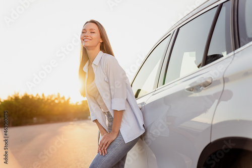 Photo portrait smiling woman standing near car laughing happy on sunset © deagreez