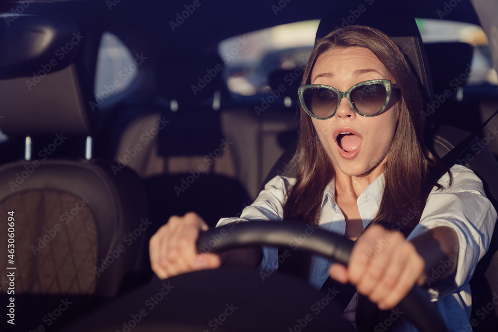 Photo of cute shocked young woman wear white shirt dark glasses riding car open mouth outside city street - obrazy, fototapety, plakaty 