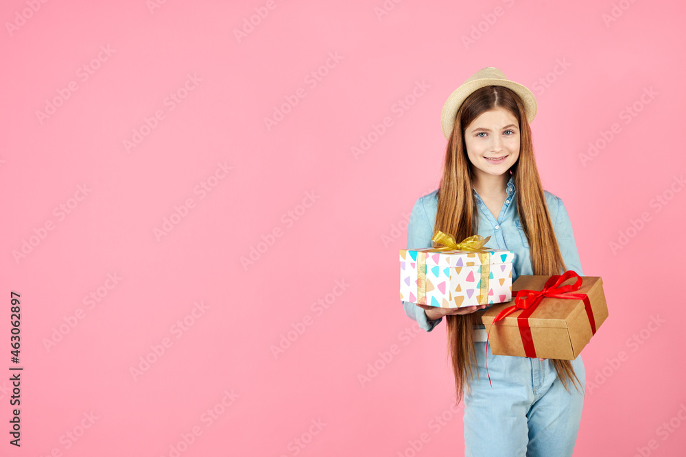 Smiling girl in jeans clothes and straw hat isolated on pink background. Valentine's Day, Women's Day, birthday concept. Hold present box with gift ribbon bow. Smiling girl in jeans clothes and straw hat isolated on pink background. Valentine's Day, Women's Day, birthday concept. Hold present box with gift ribbon bow.