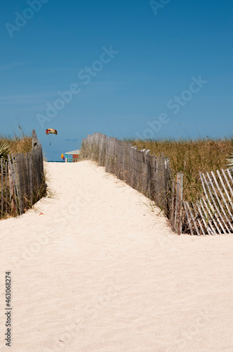The beautiful white sand beach in Miami, Florida. In the background the blue sky and a parasailing flying