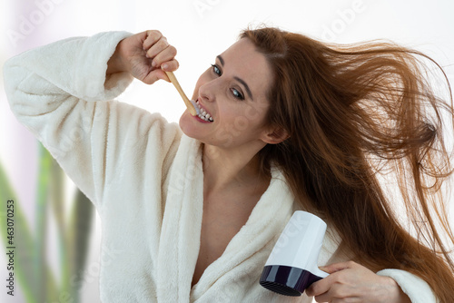 Quadro su tela Middle-aged woman combing hair and brushing teeth in a hurry