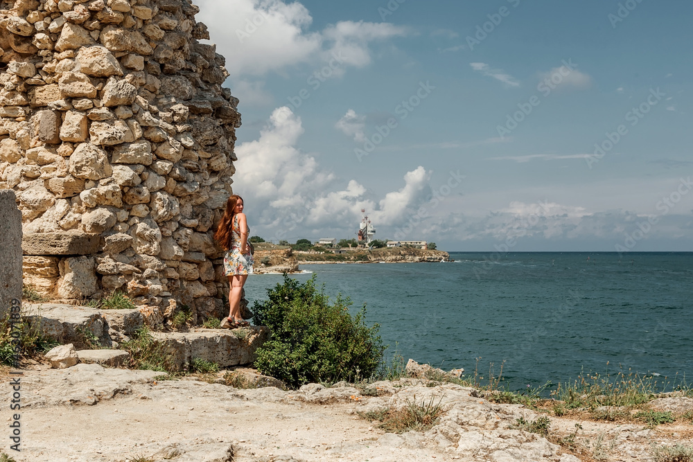 A girl in a dress travels to the ancient ruins of the fortress. Tourism in Crimea.