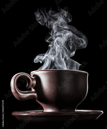 Brown ceramic cup of fresh steaming fragrant aromatic morning hot coffee over black background. Smoke from hot coffee.