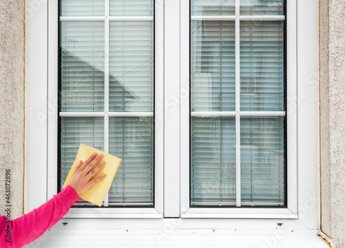  woman hand cleaning white pvc window 