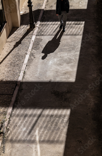 Man in black suit walking on path with sunlight and shadow