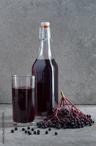 Elderberry syrup in glass bottle with the elderberries