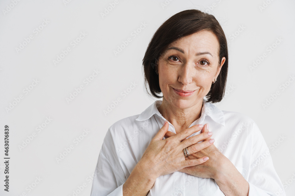 European mature woman smiling while holding her hands on chest European mature woman smiling while holding her hands on chest