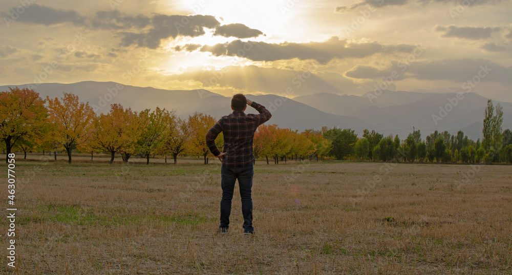 a man watching the sunset in the autumn season. a man watching the sunset in the autumn season.