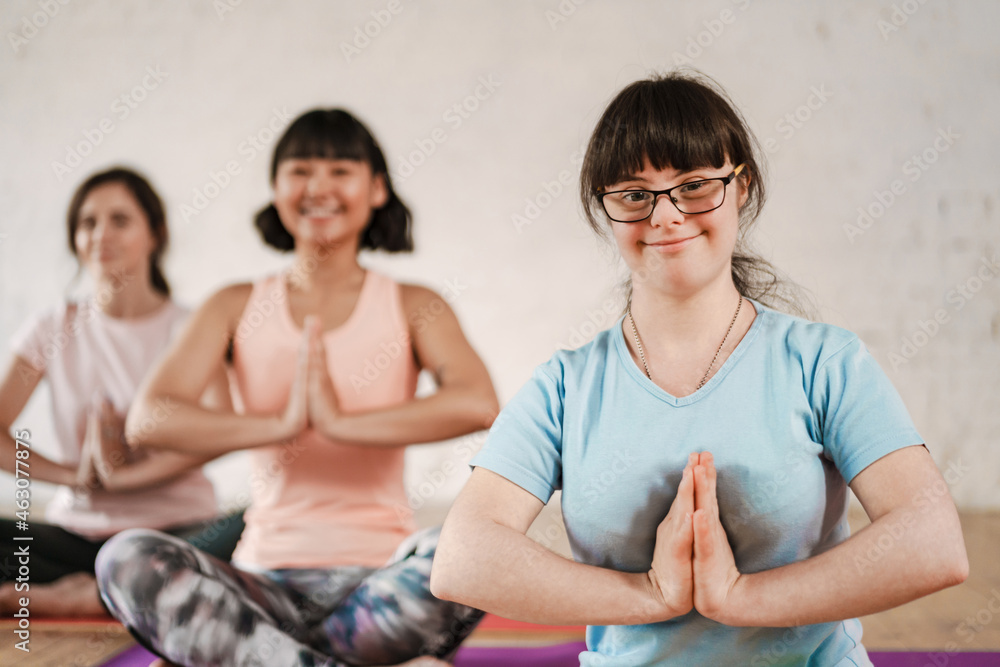 Young woman with down syndrome meditating during yoga class with coach