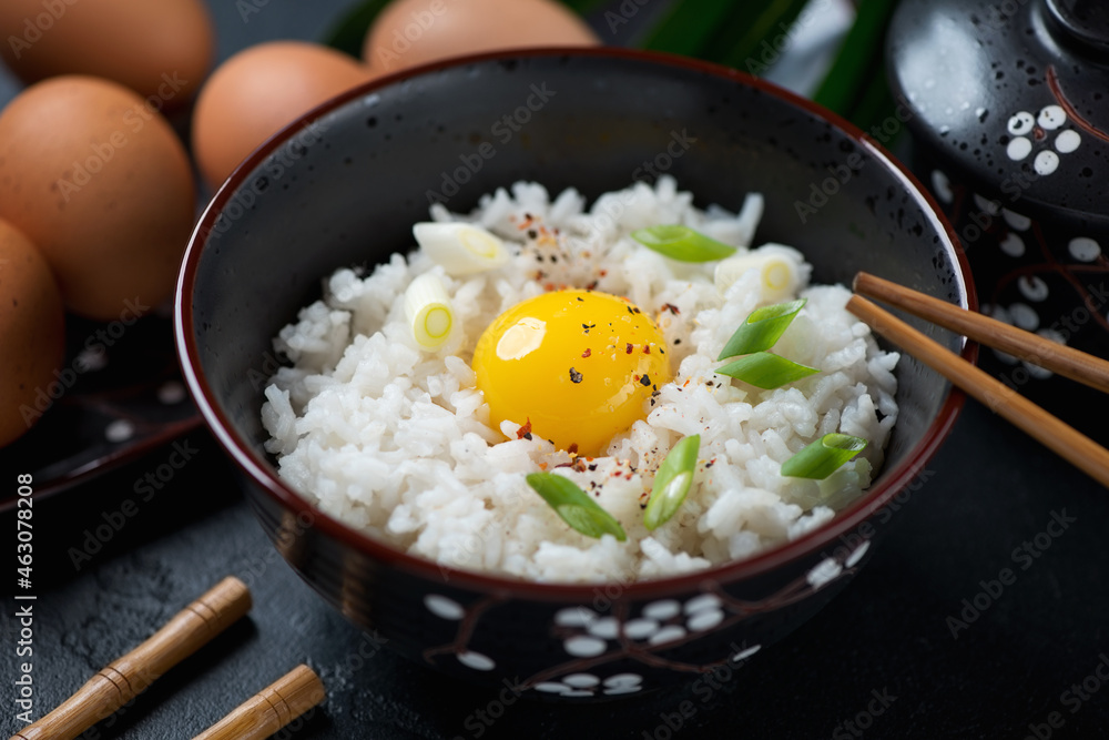 Close-up of tamago kake gohan or japanese warm rice mixed with a raw chicken egg and served in a black bowl, studio shot Close-up of tamago kake gohan or japanese warm rice mixed with a raw chicken egg and served in a black bowl, studio shot