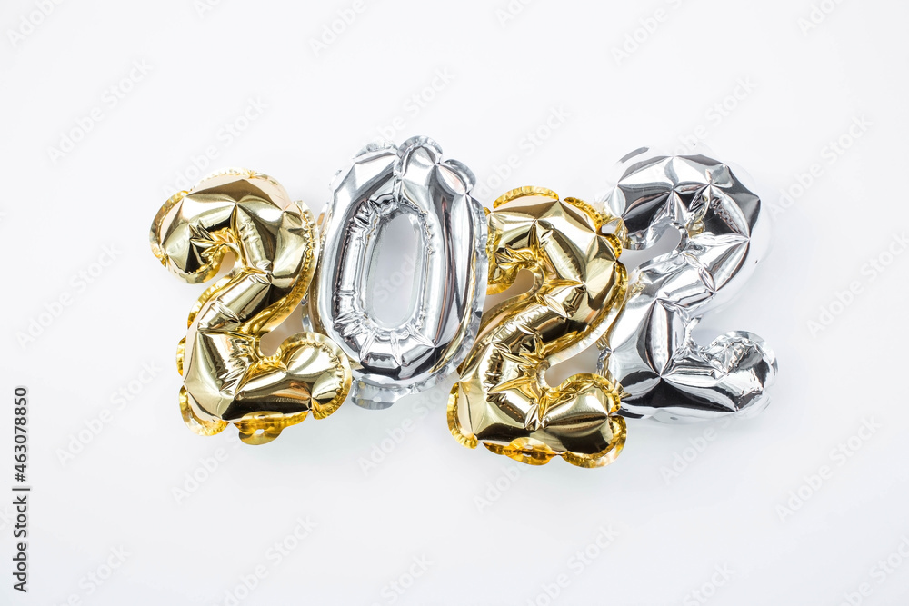 Banner. Happy New Year holiday. Balloons made of gold and silver foil with the number 2022 on a white background. Flat lay. Banner. Happy New Year holiday. Balloons made of gold and silver foil with the number 2022 on a white background. Flat lay.