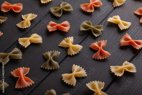 Dry farfalle tricolore pasta pattern. Uncooked Macaroni. Heap of raw traditional italian pasta on a wooden table.