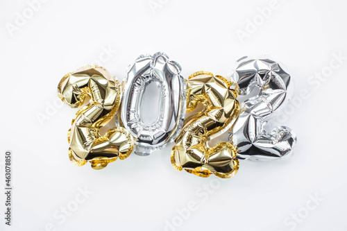 Banner. Happy New Year holiday. Balloons made of gold and silver foil with the number 2022 on a white background. Flat lay.