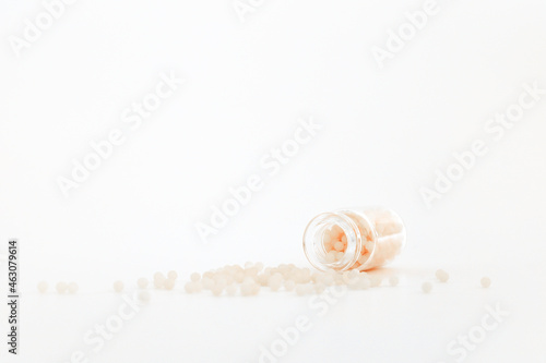 Close-up image of homeopathic globules in glass bottle on white background. Homeopathy pharmacy, herbal, natural medicine, alternative homeopathy medicine, healthcare. Free space, copy space.