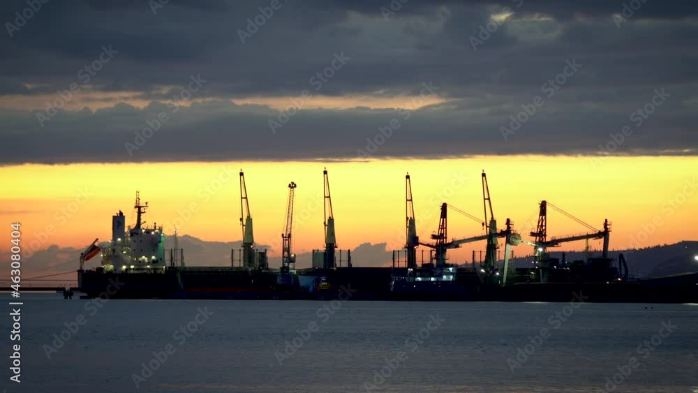 Cargo ship loading at sunset in port Cargo ship loading at sunset in port