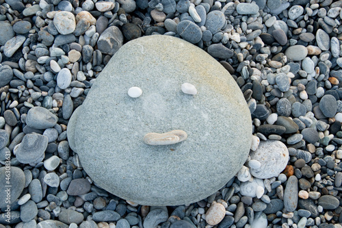 Face made on a beach with stones and pebbles