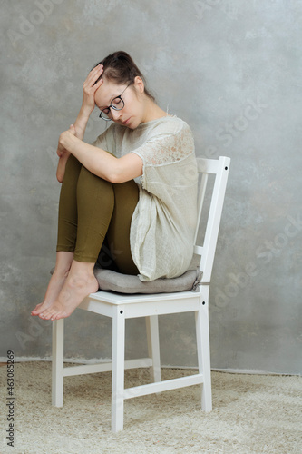woman sitting on chair with headache and closed eyes