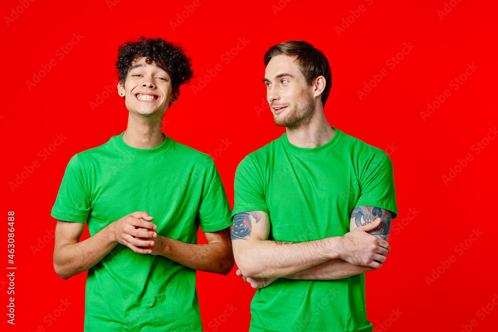 Two cheerful friends in green t-shirts communicating emotions red background Two cheerful friends in green t-shirts communicating emotions red background
