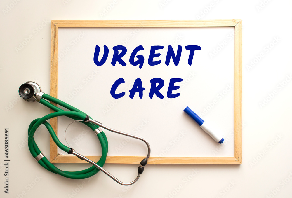The text URGENT CARE is written on a white office board. Nearby is a stethoscope. The text URGENT CARE is written on a white office board. Nearby is a stethoscope.