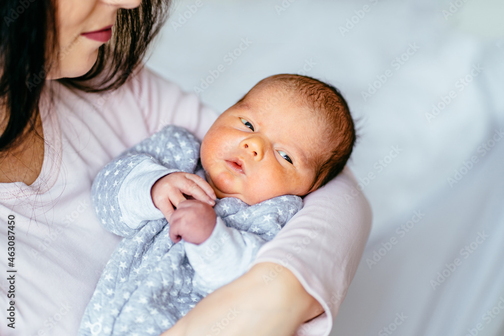 Close up of mother holding cute newborn baby boy in her arms. Sleepless baby with open eyes look at everything Close up of mother holding cute newborn baby boy in her arms. Sleepless baby with open eyes look at everything