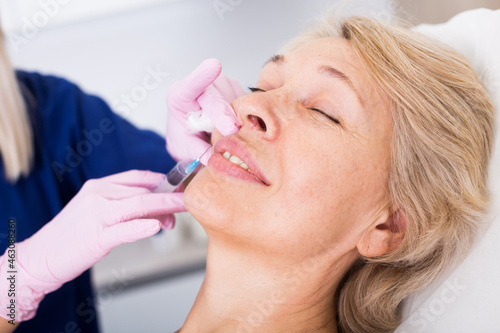 Portrait of woman during beauty facial injections in medical esthetic office.