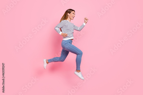Full size profile photo of young funny brown hairdo lady run wear shirt jeans sneakers isolated on pink background