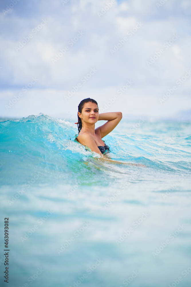 Young woman in turquoise ocean wave