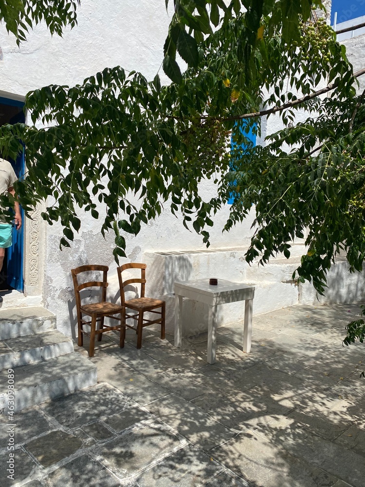 two chairs and a table on a shaded terrace under an Acacia tree