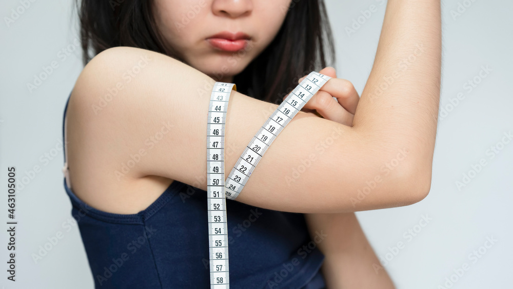 Asian women raise their arms to measure arm circumference with a white