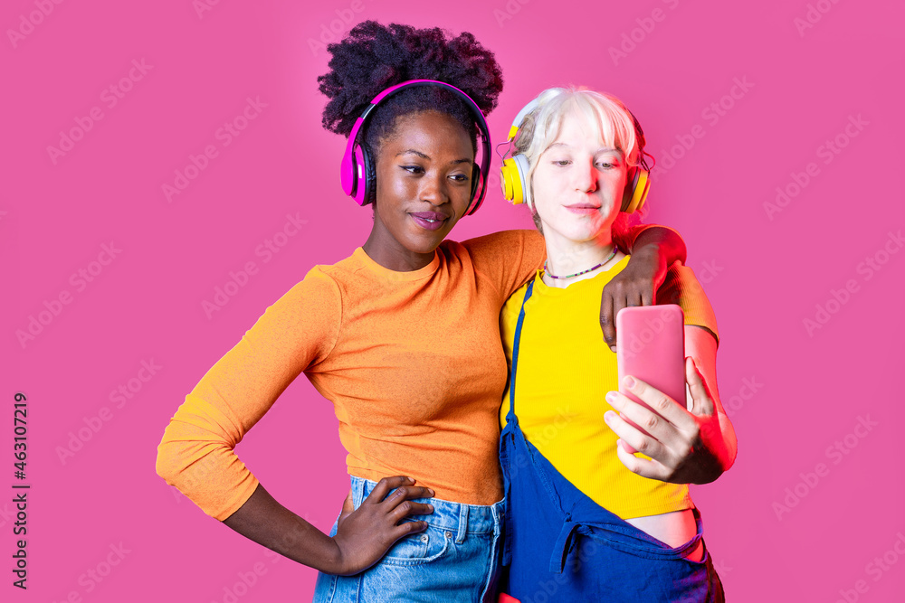 Two young diverse women best friends isolated taking selfie using smartphone smiling happy and positive Two young diverse women best friends isolated taking selfie using smartphone smiling happy and positive