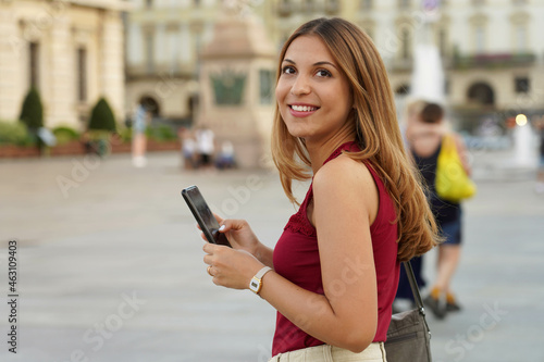 Candid thoughtful girl holds mobile phone for shopping online e-commerce outdoor. Copy space.