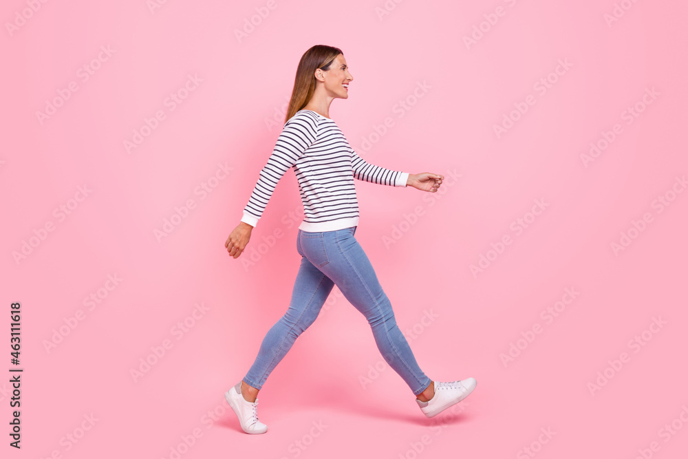 Full length profile photo of young nice brown hairdo lady go wear shirt jeans sneakers isolated on pink background Full length profile photo of young nice brown hairdo lady go wear shirt jeans sneakers isolated on pink background