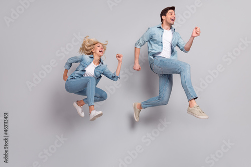Full length body size view of beautiful handsome friends friendship jumping running isolated over grey pastel color background
