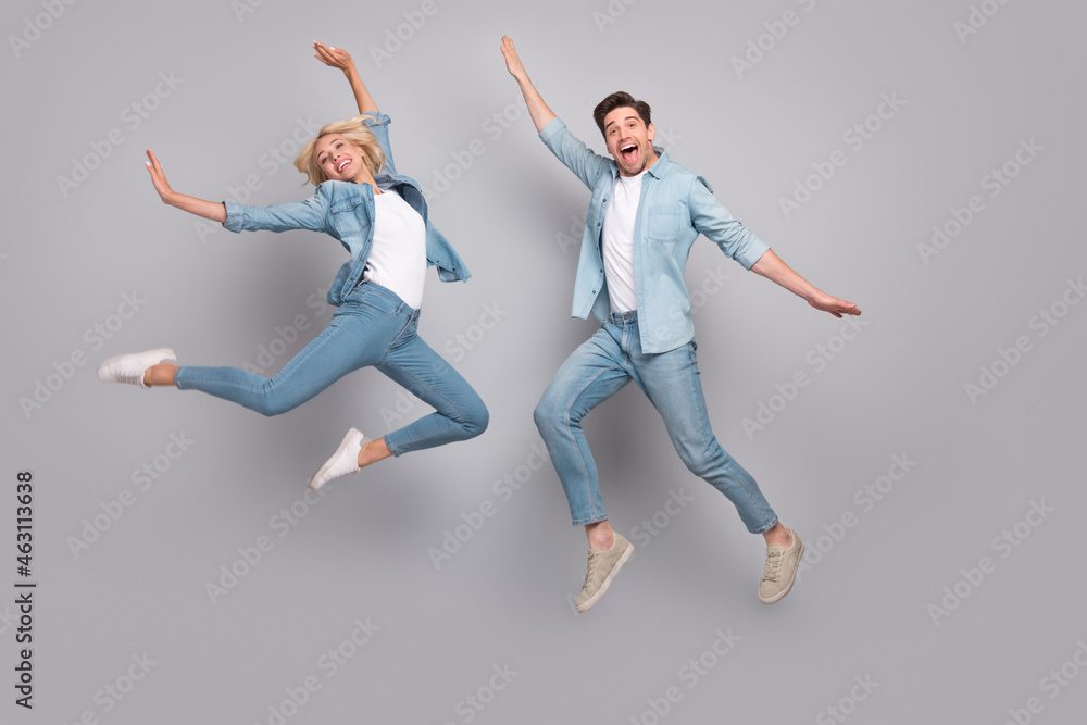 Photo of energetic sporty lover couple jump enjoy flight wear casual jeans outfit isolated grey color background