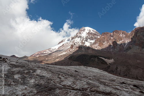 A cloudless view on Mount Kazbeg in Caucasus, Georgia. There slopes are barren and stony below the snow-capped peak and the Gergeti Glacier. Tranquillity. Natural remedy. Massive glacier foot