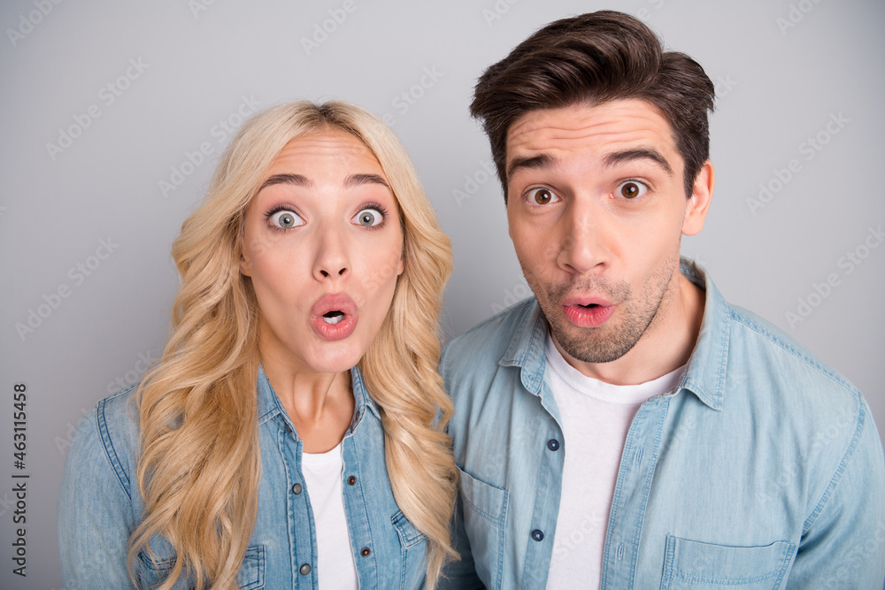 Photo of young couple look amazed shocked omg wow reaction information isolated over grey color background Photo of young couple look amazed shocked omg wow reaction information isolated over grey color background