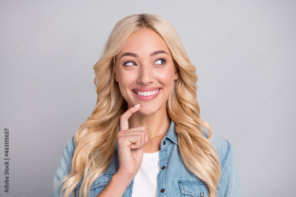 Photo of young woman happy positive smile finger touch chin curious think look empty space isolated over grey color background Photo of young woman happy positive smile finger touch chin curious think look empty space isolated over grey color background