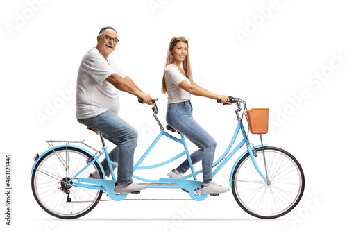 Young woman and a mature man in white t-shirts and jeans riding a tandem bicycle