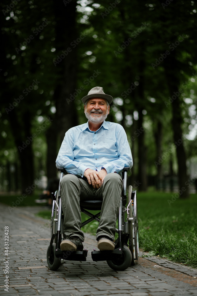 Adult disabled man in wheelchair holds paper sheet - obrazy, fototapety, plakaty 
