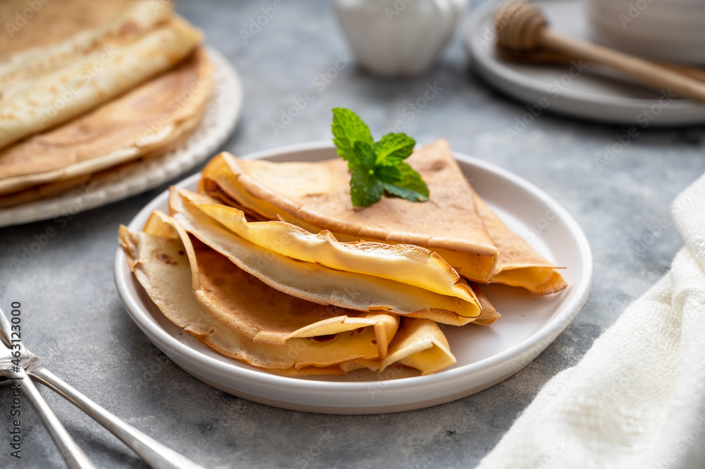 Golden crepes with jam and honey, on grey background. Golden crepes with jam and honey, on grey background.