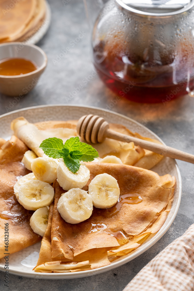 close up cepes or thin pancakes, served with honey and cup of tea, on grey background. close up cepes or thin pancakes, served with honey and cup of tea, on grey background.