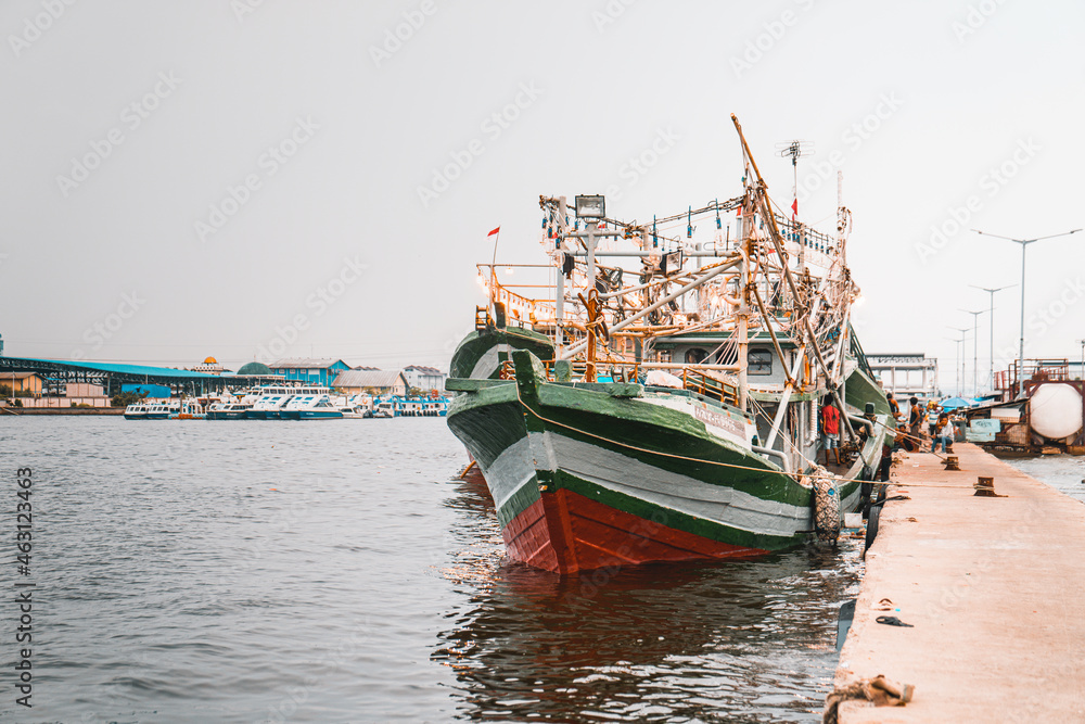 Fishing boat tied to a pier on a  gloomy day in Indonesia - obrazy, fototapety, plakaty 