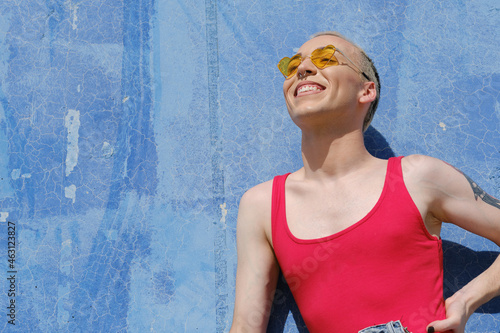 Young non-binary person wearing sunglasses and smiling while posing outdoors. photo