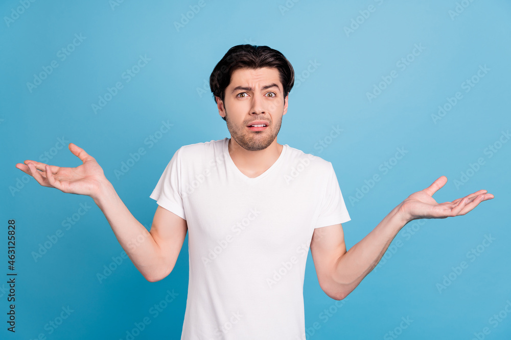 Photo of unsure troubled guy shrug shoulders confused face wear white t-shirt isolated blue color background - obrazy, fototapety, plakaty 