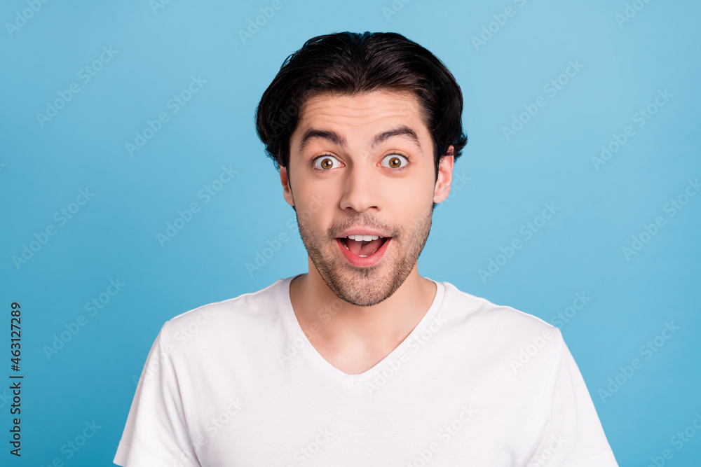 Photo of amazed surprised funky guy omg sale reaction open mouth wear white t-shirt isolated blue color background Photo of amazed surprised funky guy omg sale reaction open mouth wear white t-shirt isolated blue color background