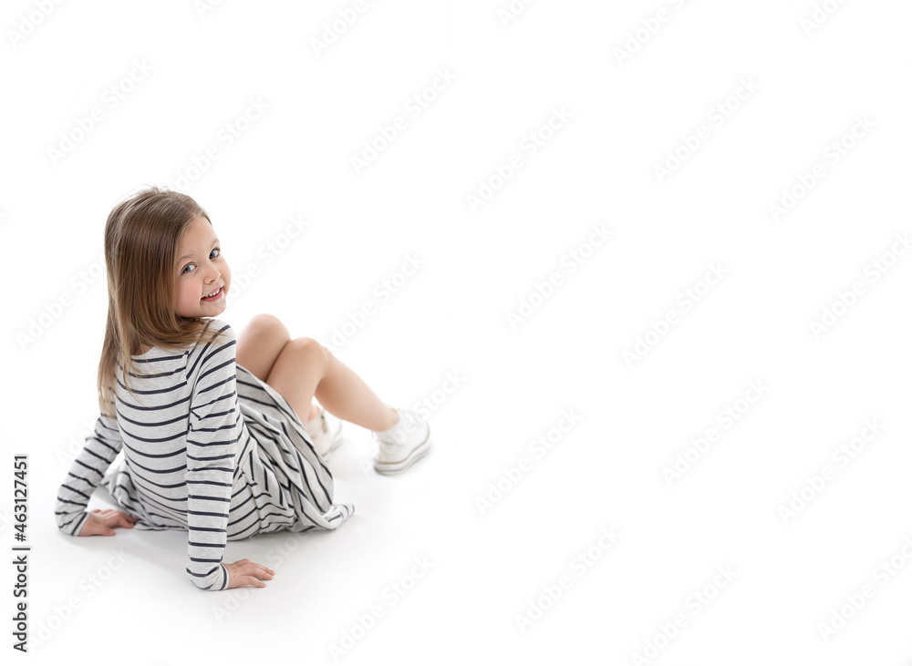 Toddler cute little girl with a mischievous cute smile is sitting on a white background and looking at camera. Copy space for text, mock up, banner Toddler cute little girl with a mischievous cute smile is sitting on a white background and looking at camera. Copy space for text, mock up, banner