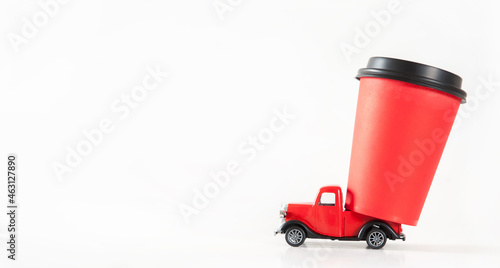 Red car carrying a paper coffee cup on a white background. Delivery of coffee. Concept. Copy space