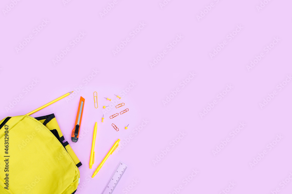 A yellow bag with school supplies scattered out.