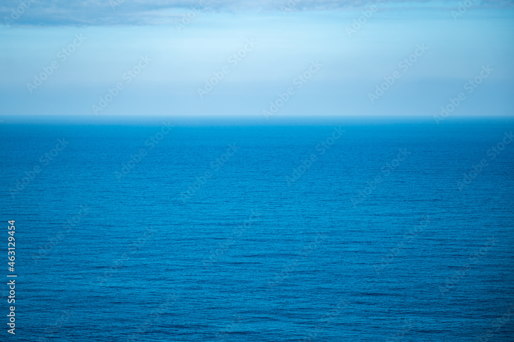 Beautiful calm and peaceful water flowing with waves towards beach with green tall trees against cloudy blue sky during daytime with no people around Beautiful calm and peaceful water flowing with waves towards beach with green tall trees against cloudy blue sky during daytime with no people around